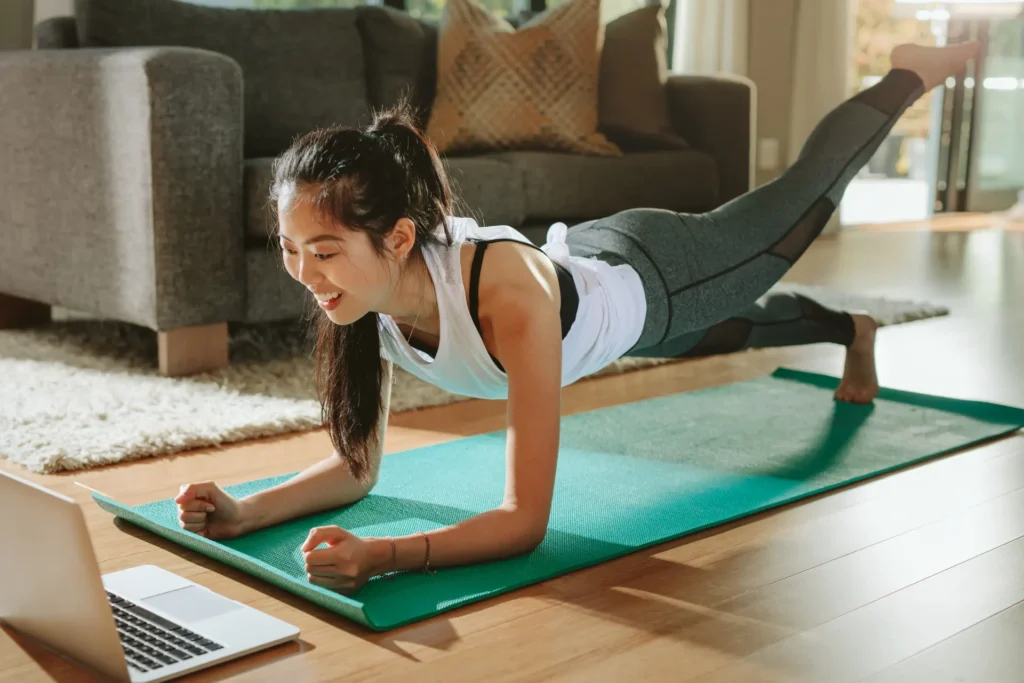 Frau schaut Sporttraining online auf dem Laptop